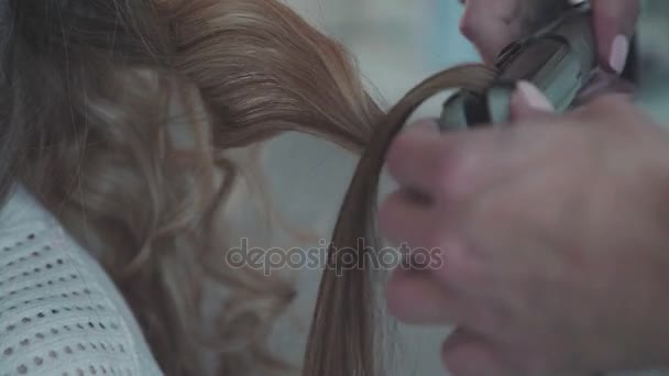 Женщина парикмахер делает кудри на светлые волосы с щипцами для завивки — стоковое видео