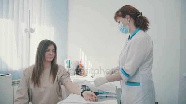 Женщина-медик делает инъекцию в руку пациентке — стоковое видео