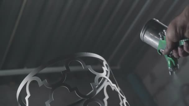 Gros plan : peindre un élément décoratif en métal à l'aide d'un pistolet aérosol .