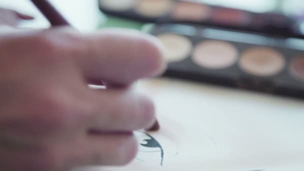 Le maquilleur crée un croquis du maquillage sur le tableau . — Video