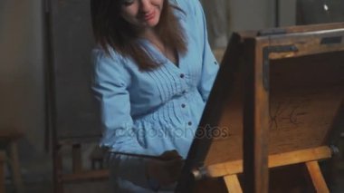 Genç kadın ressam boyalar bir resim ve gülümsüyor. Boya ile çizim.