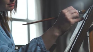 Sanatçının tuval üzerine bir kadın boyar ve geniş bir fırça smear.