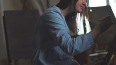 Sanatçı Göksel mavi elbiseli çizer, müzik ve gülümsüyor için dinler