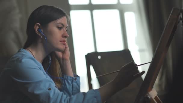 Genç sanatçı boyar ve Mp 3 çalar müzik dinler — Stok video