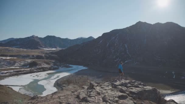 Одинокий путешественник в горах смотрит на горную долину и реку — стоковое видео