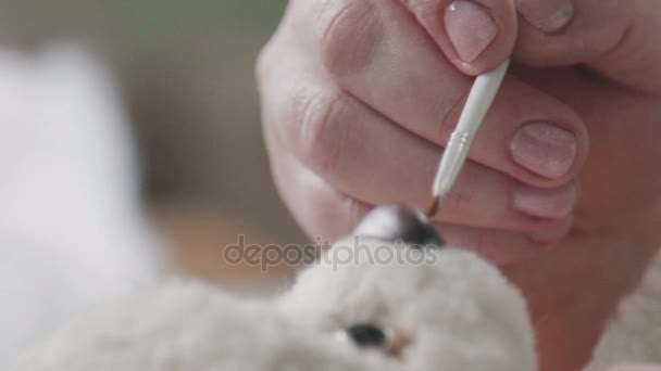 The process of creating a teddy bear: the master draws a nose toy. — Stock Video