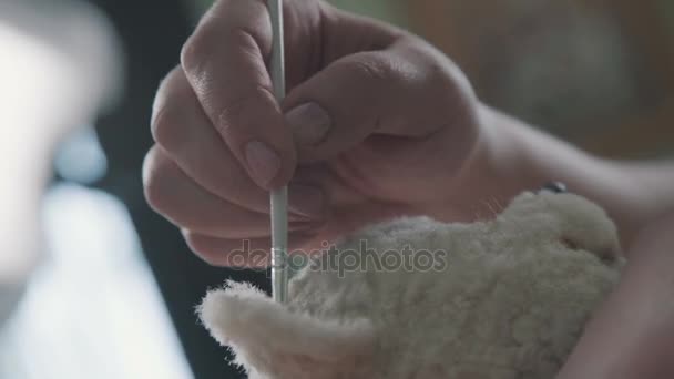 Proceso de creación de un osito de peluche: maestro pinta las orejas con un juguete . — Vídeo de stock
