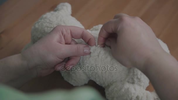 Mãos femininas costurar um ursinho de pelúcia em um estilo antiquado . — Vídeo de Stock