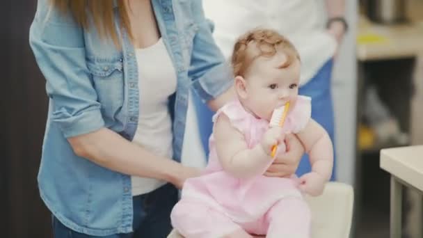 En halv-årig baby i en rosa klänning repor hennes tuggummi. Baby med mamma — Stockvideo