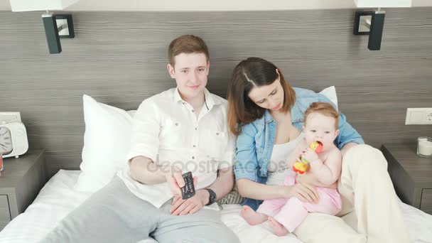 Giovane con la sua famiglia accende la TV, utilizzando un pannello di controllo remoto — Video Stock