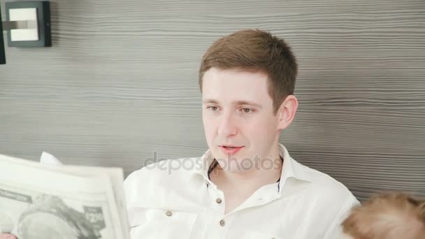 A young man with his family reads the morning newspaper. — Stock Video