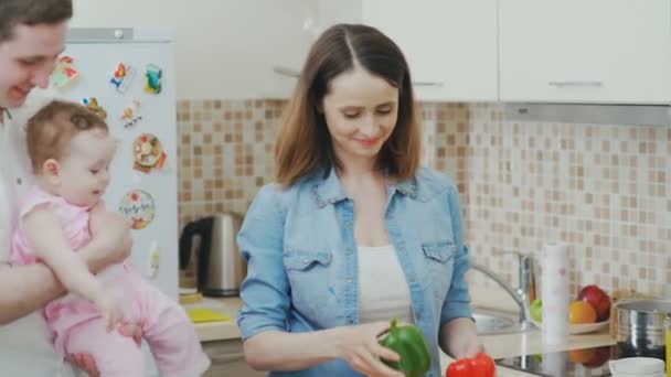 Ранкова сім'я: мама готує їжу, маленька дитина спостерігає за процесом — стокове відео