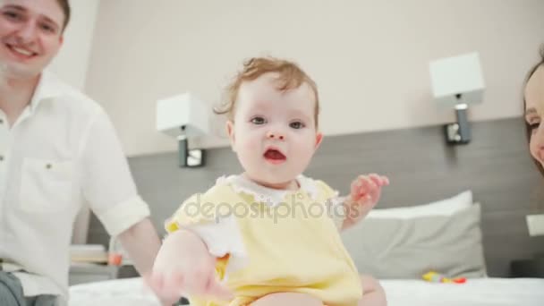 Encantador bebé se arrastra en la cama, los padres cuidan de su hija . — Vídeos de Stock