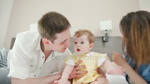 A happy couple in love on the bed playing with their child — Stock Video