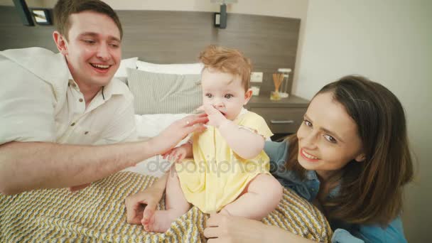 Un bebé encantador se arrastra en la cama, los padres cuidan de su hija . — Vídeos de Stock