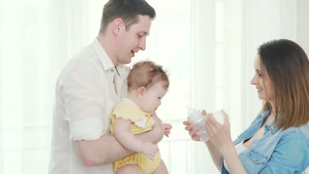 Father holds the baby in his arms, the mother feeds from the bottle — Stock Video