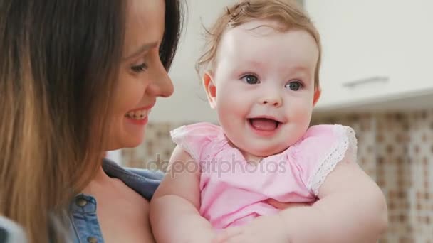 Una madre joven y una hija sonriente en sus manos: un retrato conjunto — Vídeo de stock