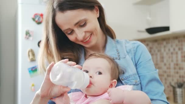 Uma bela mãe alimenta seu bebê de uma mamadeira com uma chupeta . — Vídeo de Stock