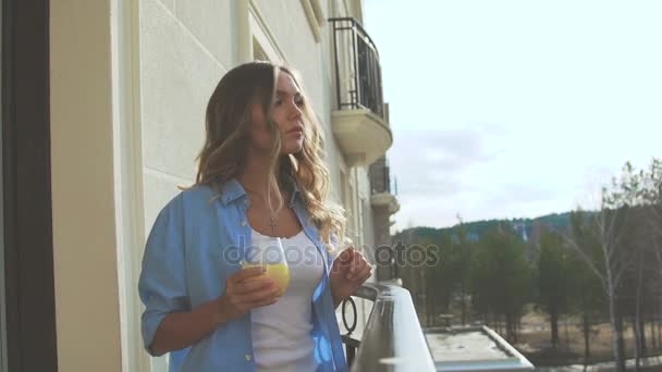 Женщина на балконе рано утром и пьет апельсиновый сок . — стоковое видео
