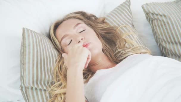 Schönes Mädchen wacht frühmorgens in ihrem Bett auf und dehnt sich — Stockvideo