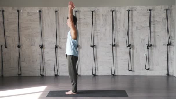 Man in a white top and gray tights performs asana Greeting the sun — Stock Video