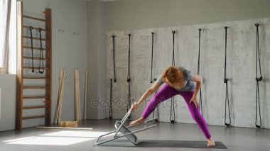 Yetişkin bir kadın yogi bir sandalye kullanarak bir asana yapar.