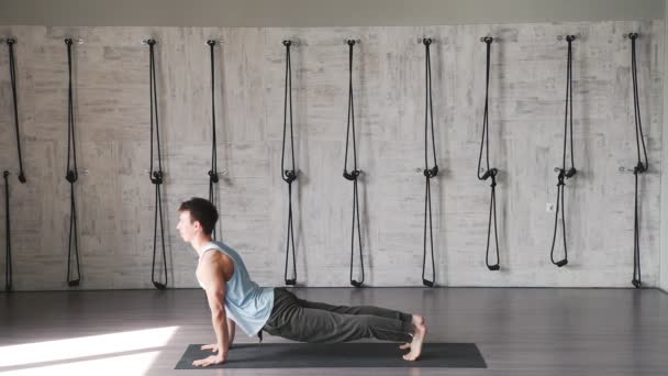 Um homem pratica ioga dentro de casa em estilo loft. Estúdio Yoga — Vídeo de Stock