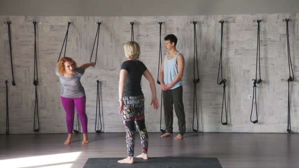 Yogastudio: två kvinnor och en man utövar yoga och gör gymnastik. — Stockvideo