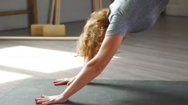 Olgun bir kadın asanas Yoga gerçekleştirir. Köpek suratların aşağı