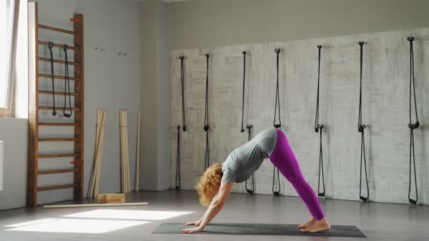 En moden kvinne øver på yoga og gjør asana "hilser på solen ". – stockvideo