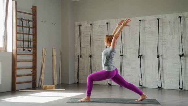 Een heldere vrouw houdt zich bezig met yoga in een lichte studio. — Stockvideo