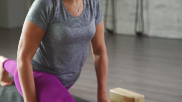 Woman is stretching, sits on a string. Yoga mat, wooden cubes blocks — Stock Video