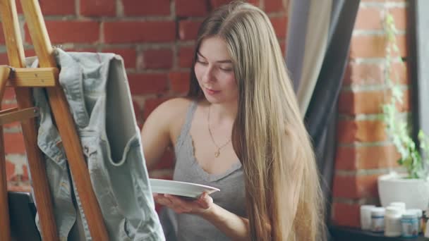 Peintures de fille aux cheveux longs avec des couleurs à l'huile sur chevalet à l'intérieur de l'atelier . — Video