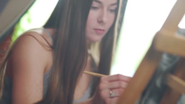 Una mujer con el pelo largo dibuja en una habitación luminosa . — Vídeos de Stock