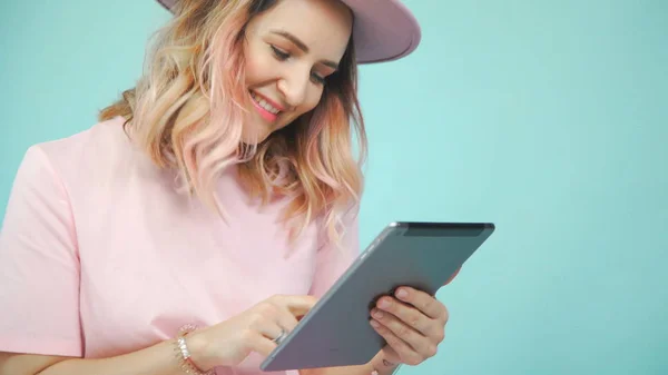 Turkuaz bir arka plan üzerinde bir tablet ile güzel güzel kadın.