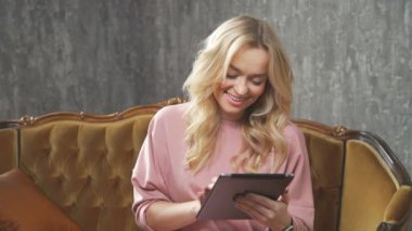 Güzel kadın kanepe stüdyoda oturup tablet kullanma.