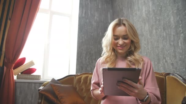 Mujer joven con estilo en un sombrero disfruta de la comunicación en una tableta . — Vídeos de Stock