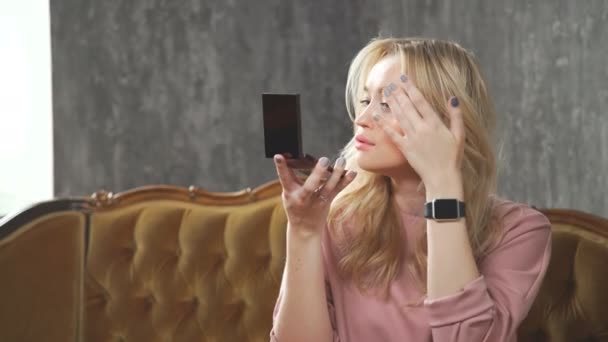 Ohromující blondýna, při pohledu na kapesní zrcátko a odstraňuje make-up. — Stock video