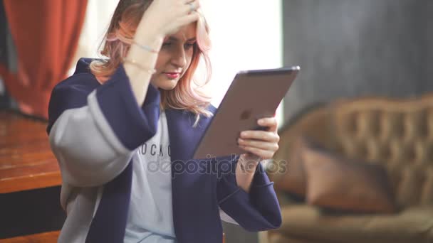 Mulher moderna com um tablet: ela se senta em uma sala e gosta de socializar . — Vídeo de Stock