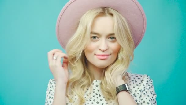 Inschrijving blonde poseren in een roze hoed, recht in de camera kijken. — Stockvideo