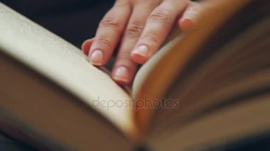 Kadının el ve bir kitap tutan parmak okuma sırasında sayfa boyunca hareket eder