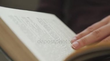 Kadının el parmakları hareket sayfalar arasındaki sulak bir kitapla tutar