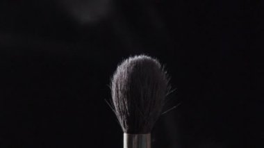 Kozmetik kozmetik toz siyah arka plan üzerine yayılan fırçayla.