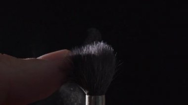 Siyah bir zemin üzerine toz fırçası: makyaj araçları.