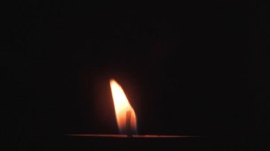 Bir mum alevi koyu arka plan üzerinde yakar. Yanan Mum