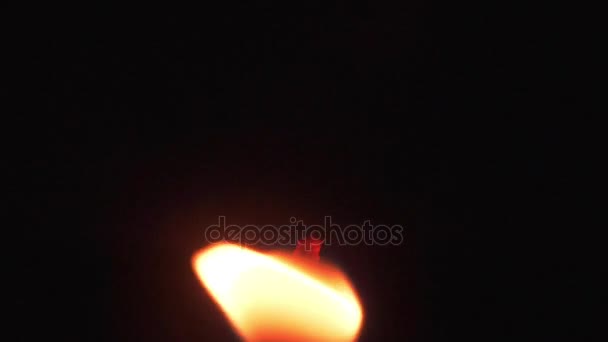 Полум'я свічки рухається на чорному тлі. Світло від полум'я свічки — стокове відео