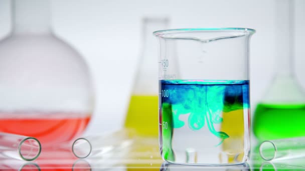 Glas för labb med vätskor inne på en vit bakgrund. — Stockvideo