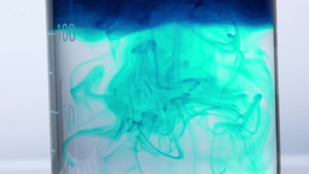 Голубой реагент добавляется в воду. окрашивание прозрачной жидкости синим цветом — стоковое видео