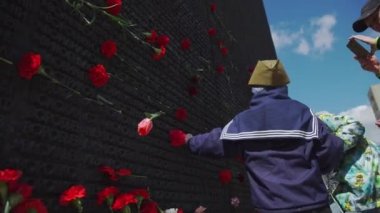 Rusya, 9 Mayıs 2017: yem-şapkalı çocuk bellek duvara karanfil bırakır