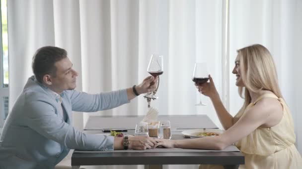 L'homme tient doucement la femme à la main, dit un toast touchant, cligner des verres — Video